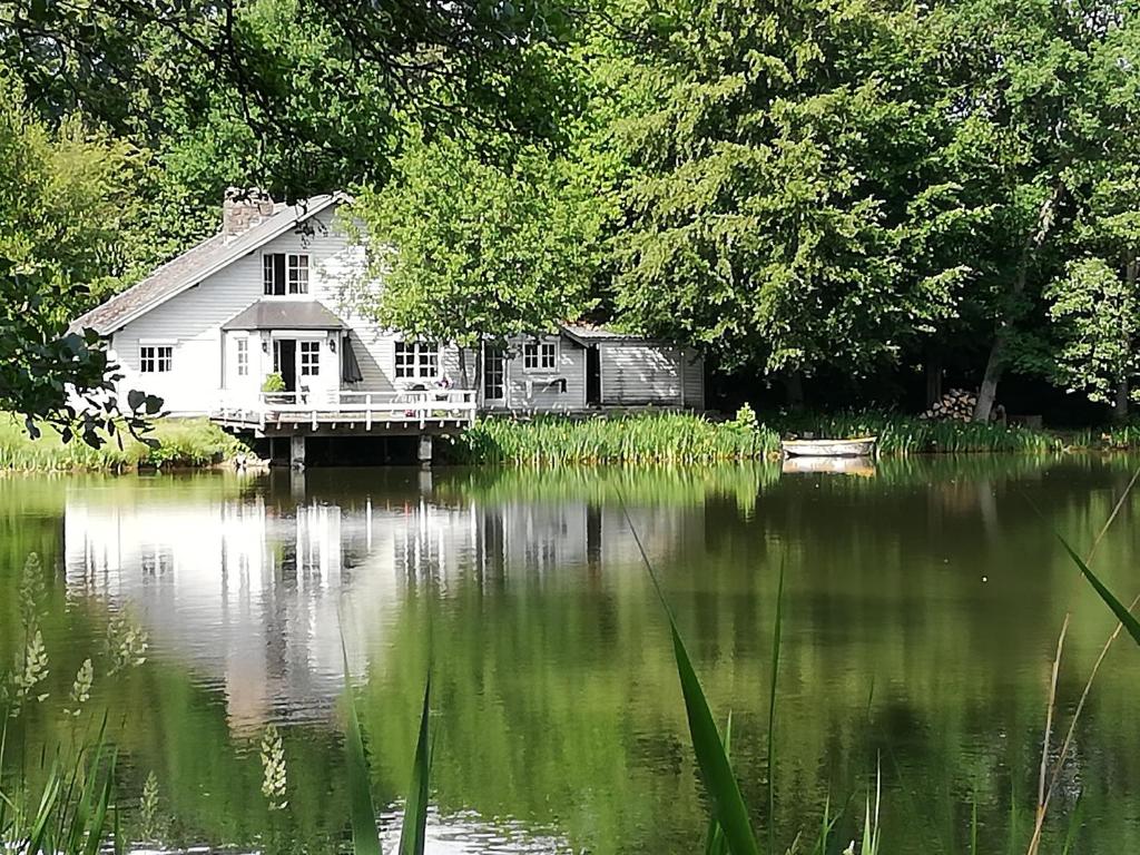 a house sitting on a lake with a dock at La maison du lac in Cul-des-Sarts