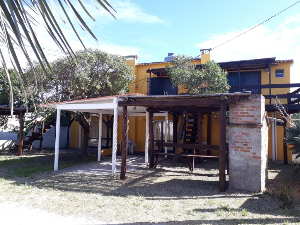 a house with a porch and a yellow building at La Casa del Caminante in Aguas Dulces