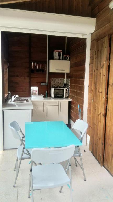 a kitchen with a blue table and white chairs at LESTEPHANIA in Le Moule