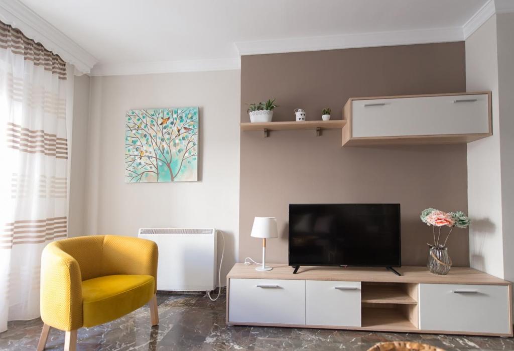 un soggiorno con TV e sedia gialla di APARTAMENTO CONVENTO ENCARNACIÓN ad Antequera