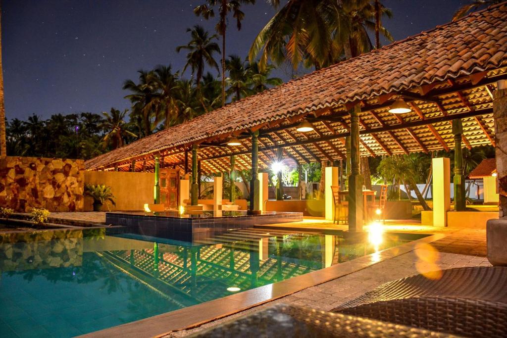 uma piscina de resort com um pavilhão à noite em Rookada Heritage em Ambalangoda