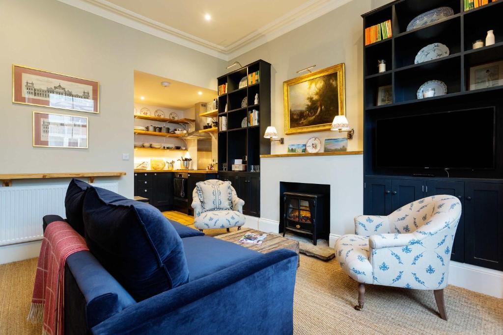 a living room with a blue couch and two chairs and a fireplace at Veeve - Sinclair Sophistication in London