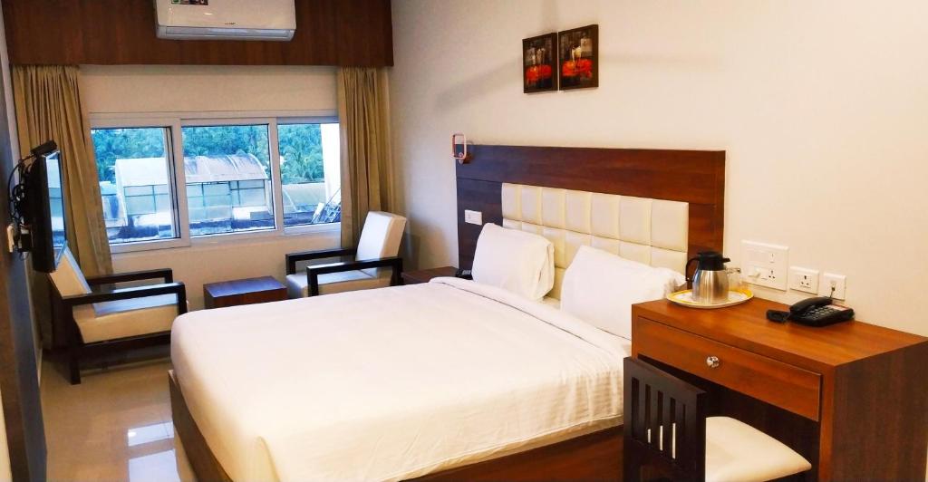 a bedroom with a bed and a desk with a telephone at Alhind Calicut Tower in Kozhikode