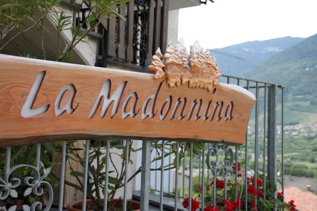 un banco de madera con un cartel en el balcón en La Madonnina, en Villa di Tirano