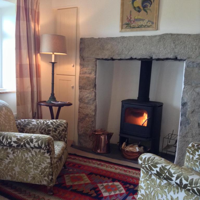a living room with a wood stove in a room at Rhiw 2 Bryn Tirion in Rhiw