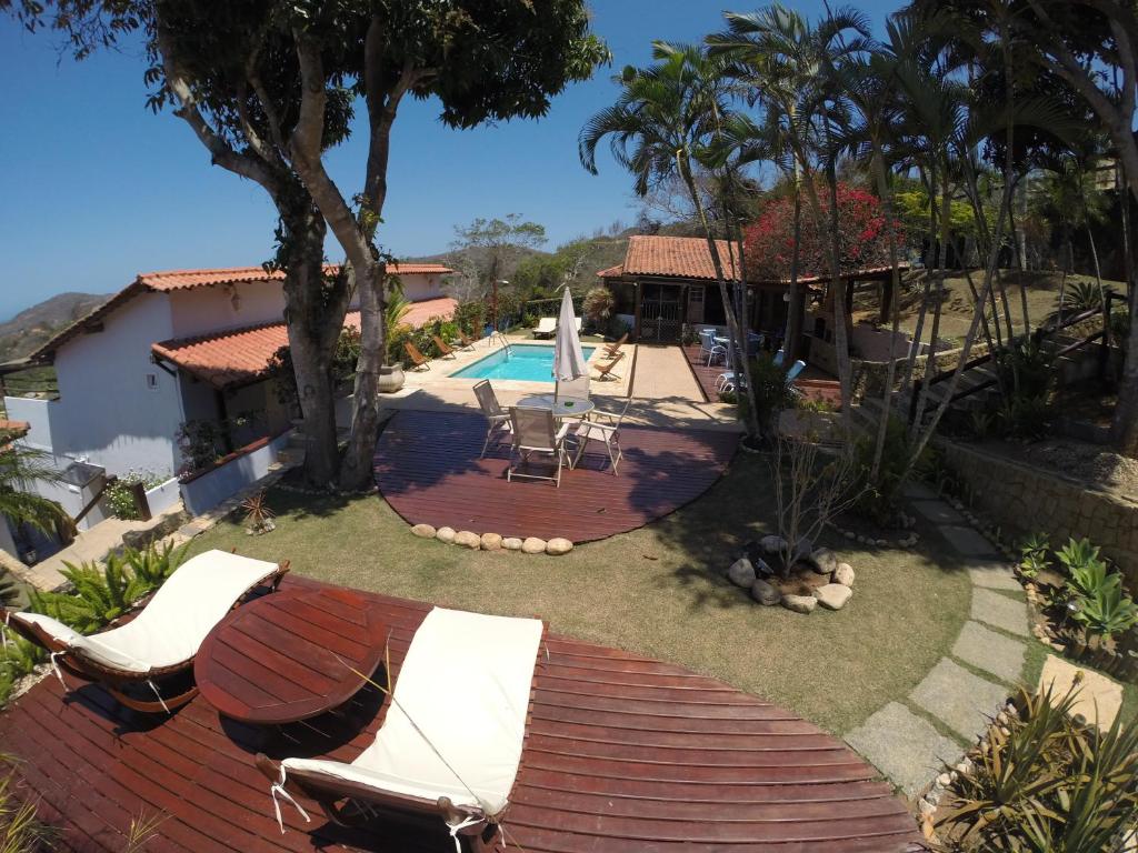 un patio trasero con piscina y terraza con sillas en Pousada Akaroa, en Búzios