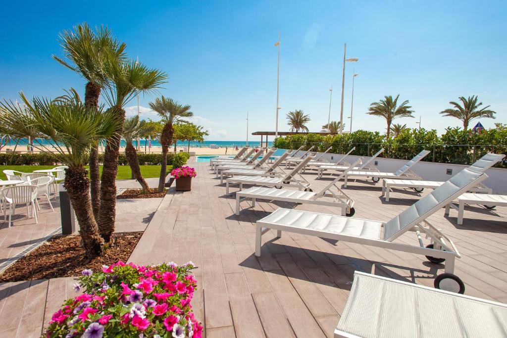 a row of white benches next to the beach at RH Bayren Hotel & Spa 4* Sup in Gandía