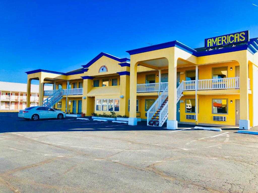 a yellow hotel with a car parked in front of it at Americas Best Value Inn-Princess Anne in Princess Anne