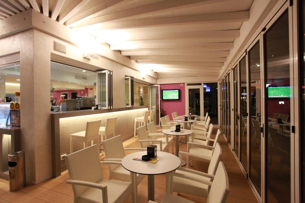 a restaurant with tables and chairs and a bar at Hotel Lux in Caorle