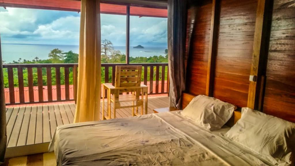 1 dormitorio con 1 cama y balcón con silla en Domus Guesthouse en Santana