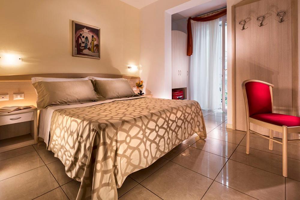 リミニにあるホテル アダのベッドルーム1室(ベッド1台、赤い椅子付)