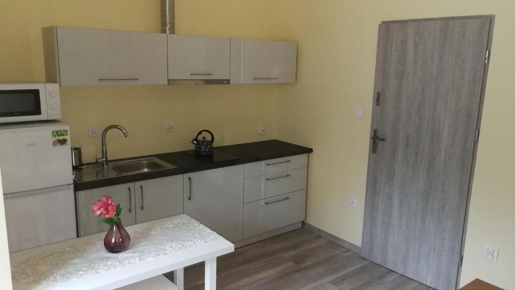 a kitchen with white cabinets and a vase of flowers on a table at Nad Strumykiem 1 in Duszniki Zdrój