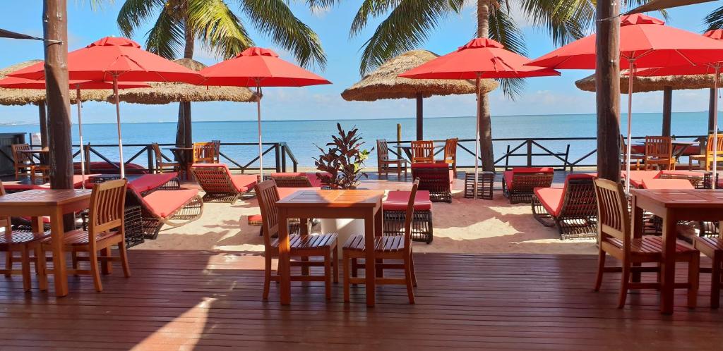 una terraza con mesas, sillas y sombrillas en la playa en Ramada Suites by Wyndham Wailoaloa Beach Fiji en Nadi