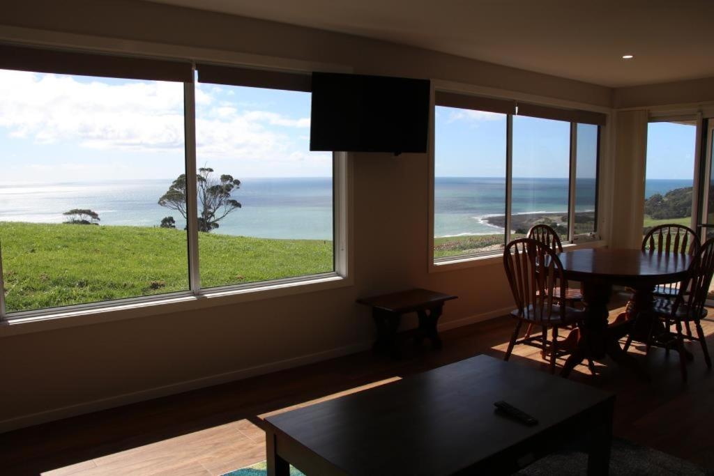 a living room with a table and a view of the ocean at Penguin Seaside Farm in Penguin