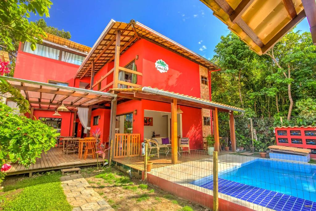 a red house with a swimming pool in front of it at i9 Embaú Flats & Suites in Itacaré