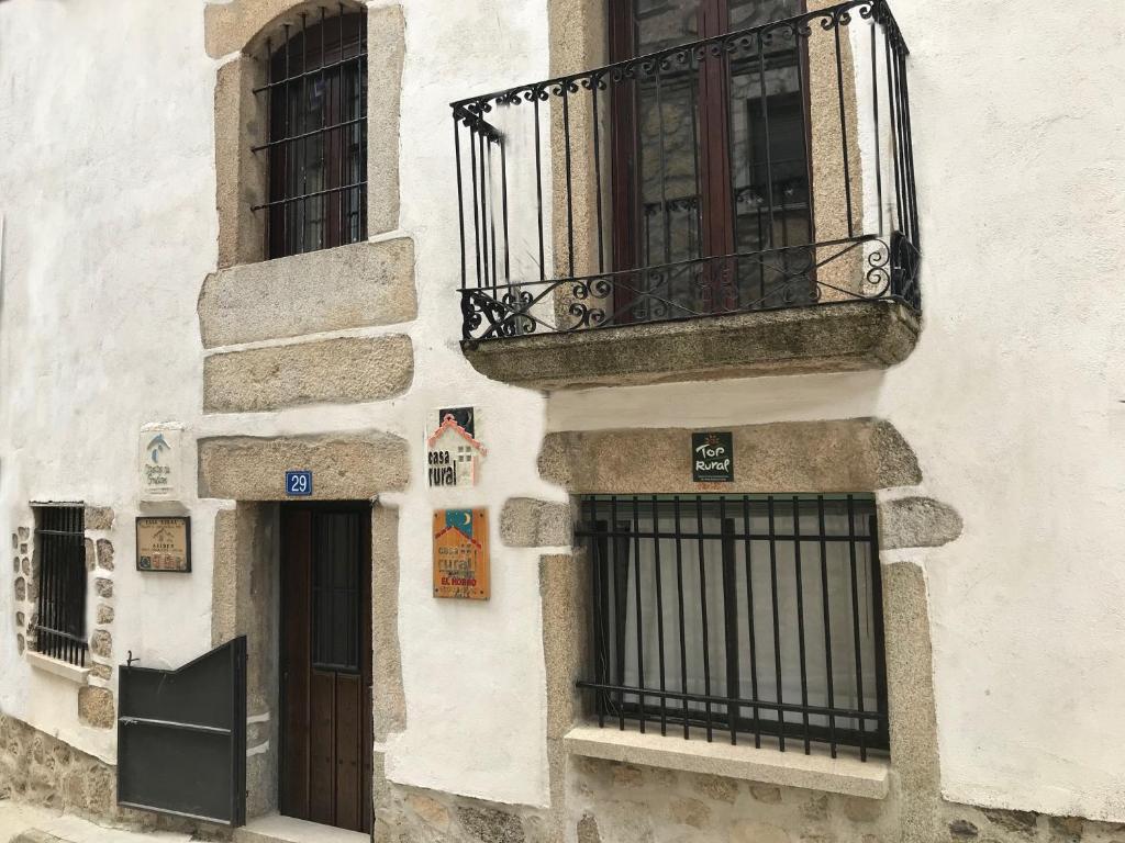 a white building with a balcony and a door at Casa del Horno in Navalonguilla