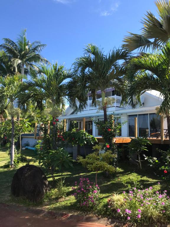 una casa con palmeras y flores delante de ella en Ravine Bleue en Saint-Louis