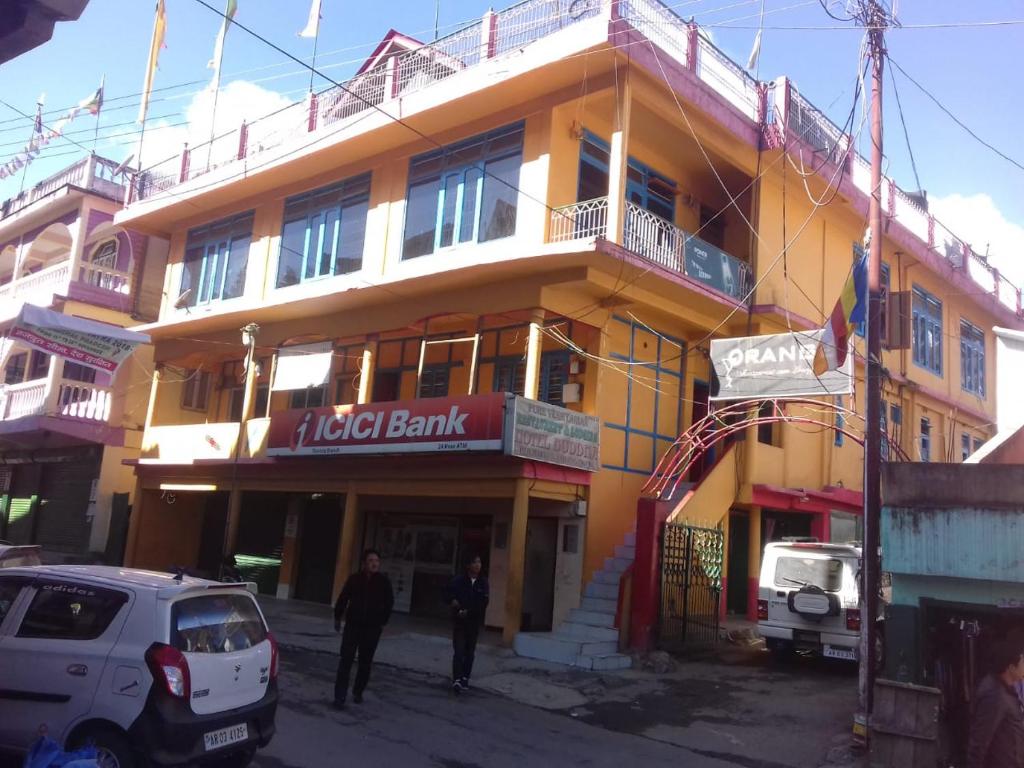 a yellow building with a man standing in front of it at Vamoose Buddha Hotel Tawang in Tawang