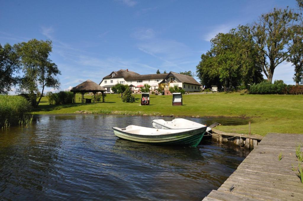 Ein Boot liegt auf dem Wasser in der Nähe eines Hauses. in der Unterkunft Ferienpension Seeblick in Neuensien