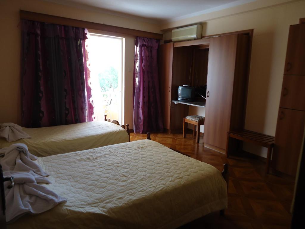a hotel room with two beds and a window at FAFALIOS Studios in Vrontádos