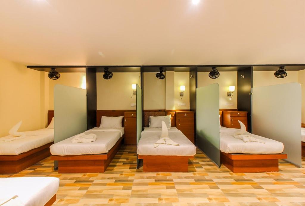 a room with three beds in a room at Blossom Dormitory For Male and Female in Mumbai