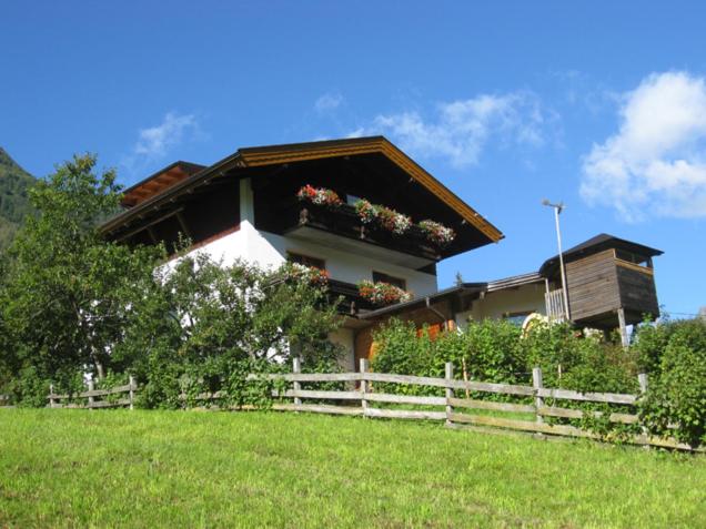 ein Haus auf einem Hügel mit einem Zaun davor in der Unterkunft Apartments Auenheim in Prägraten