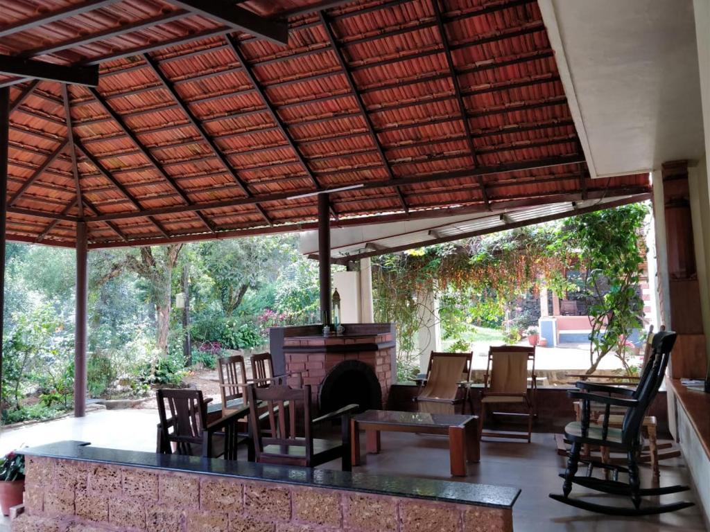 an outdoor patio with a fireplace and tables and chairs at Kabbe Holidays in Madikeri
