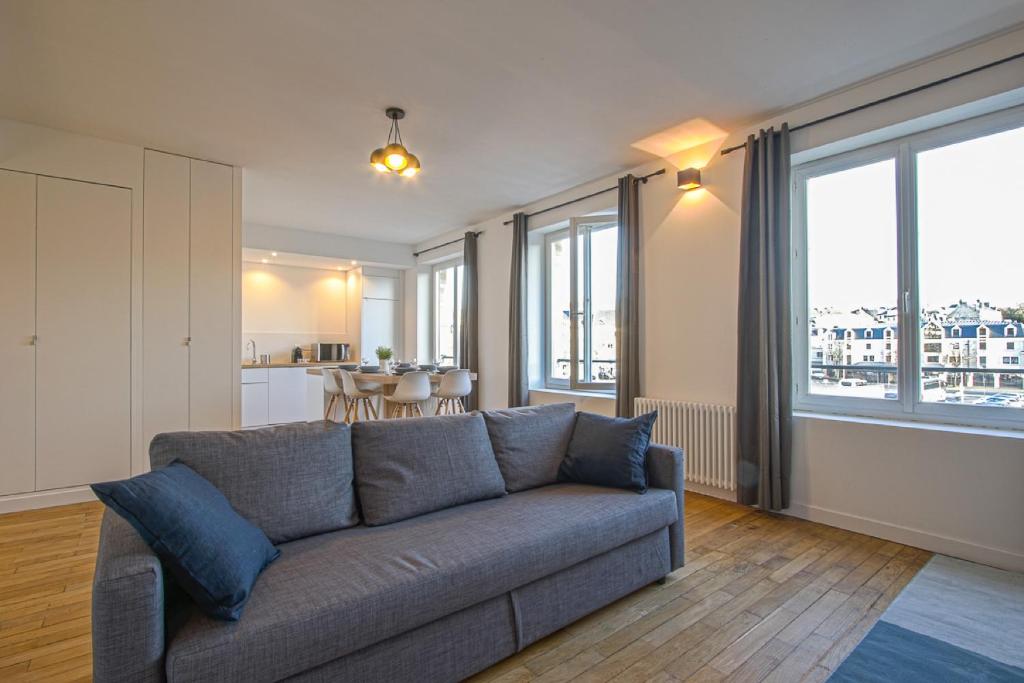 a living room with a gray couch and a kitchen at Port de Caen Haut de Gamme in Caen