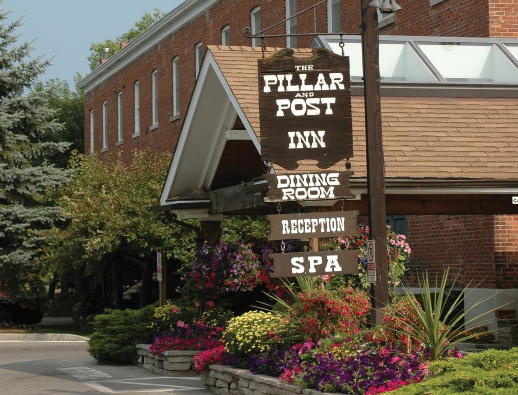 a sign in front of a brick building with flowers at Pillar and Post Inn & Spa in Niagara-on-the-Lake
