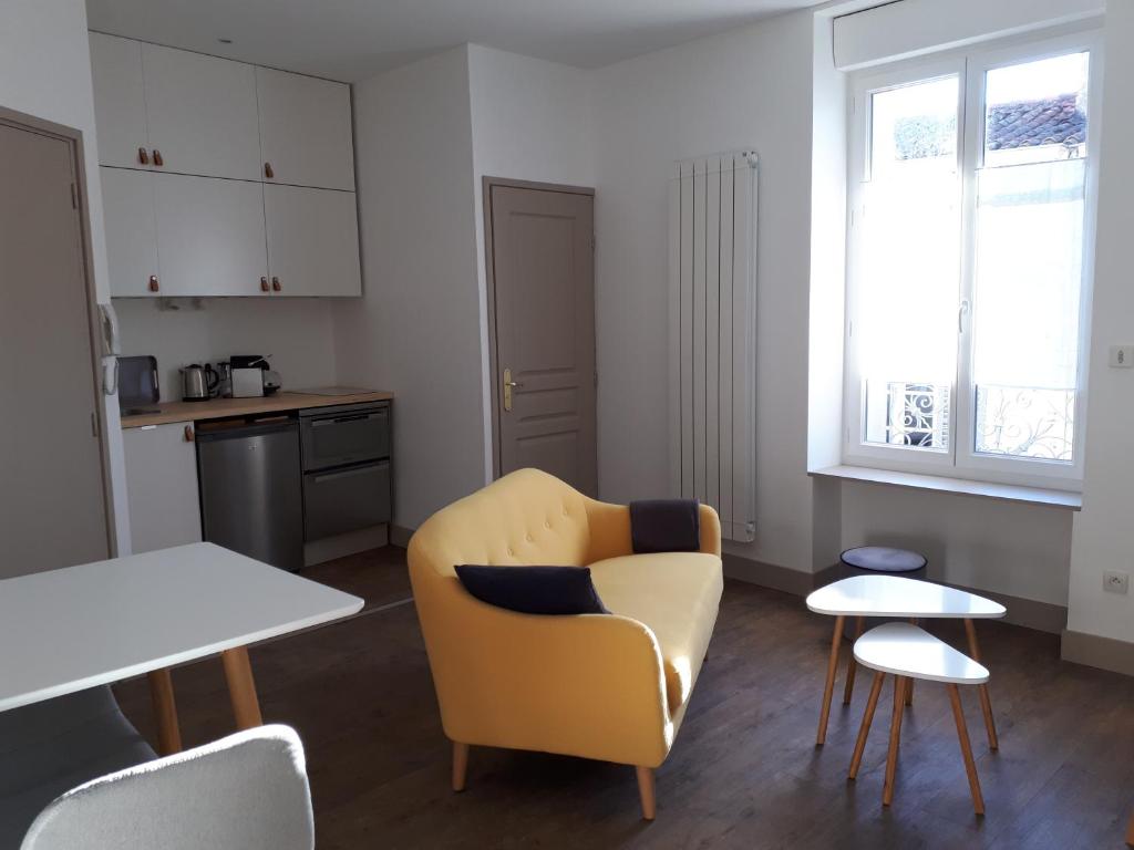 uma sala de estar com uma cadeira amarela e uma mesa em Un Appart en Ville em Niort