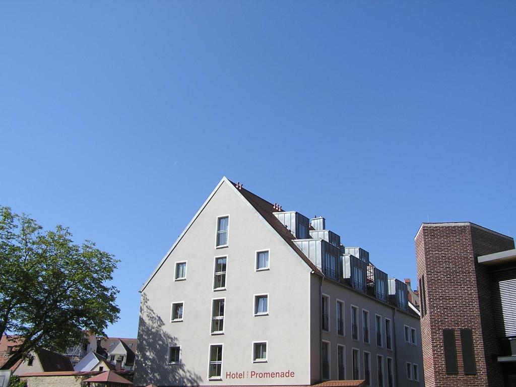 um edifício branco em frente a alguns edifícios em Hotel zur Promenade em Donauwörth