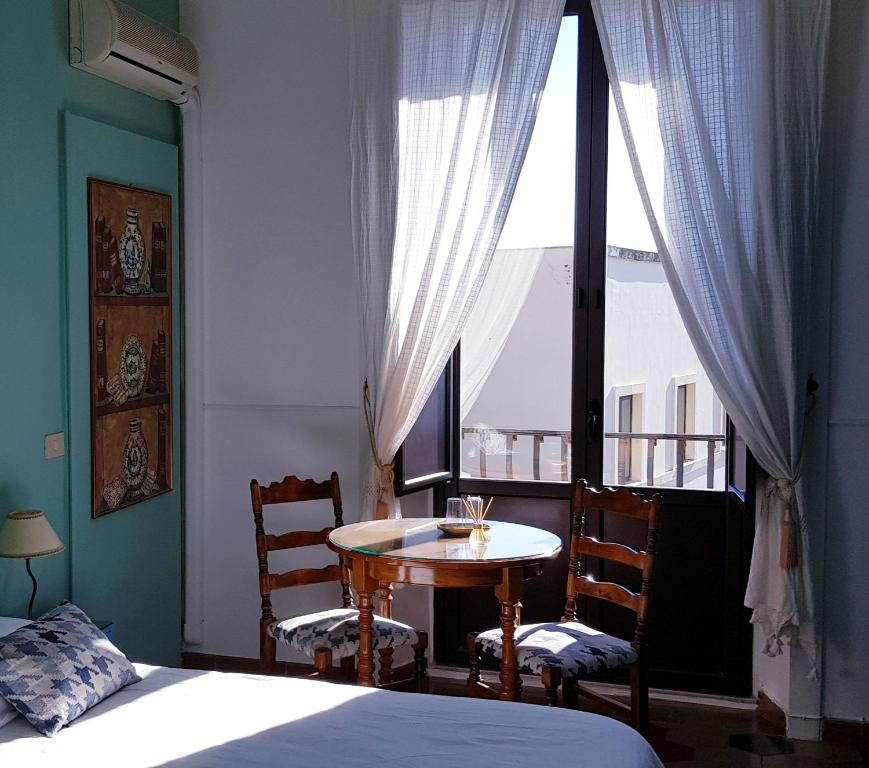 a bedroom with a table and chairs and a window at Villa Floresta Taormina in Taormina