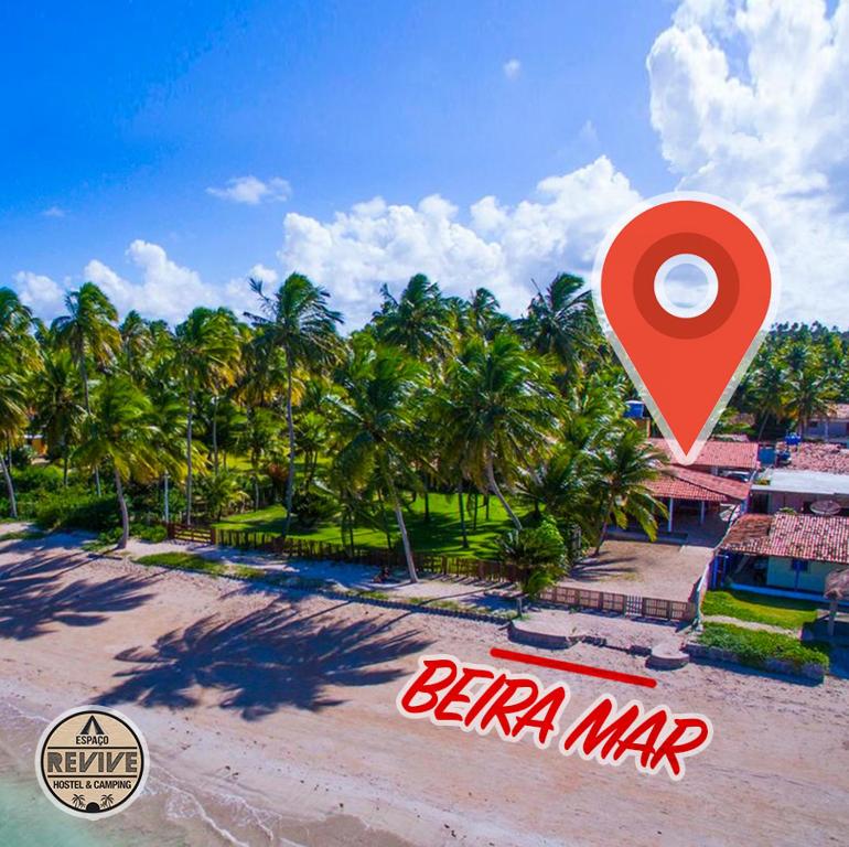 un marcador rojo en una playa con palmeras en Espaço Revive Guesthouse e Camping - PÉ NA PRAIA, en Maragogi