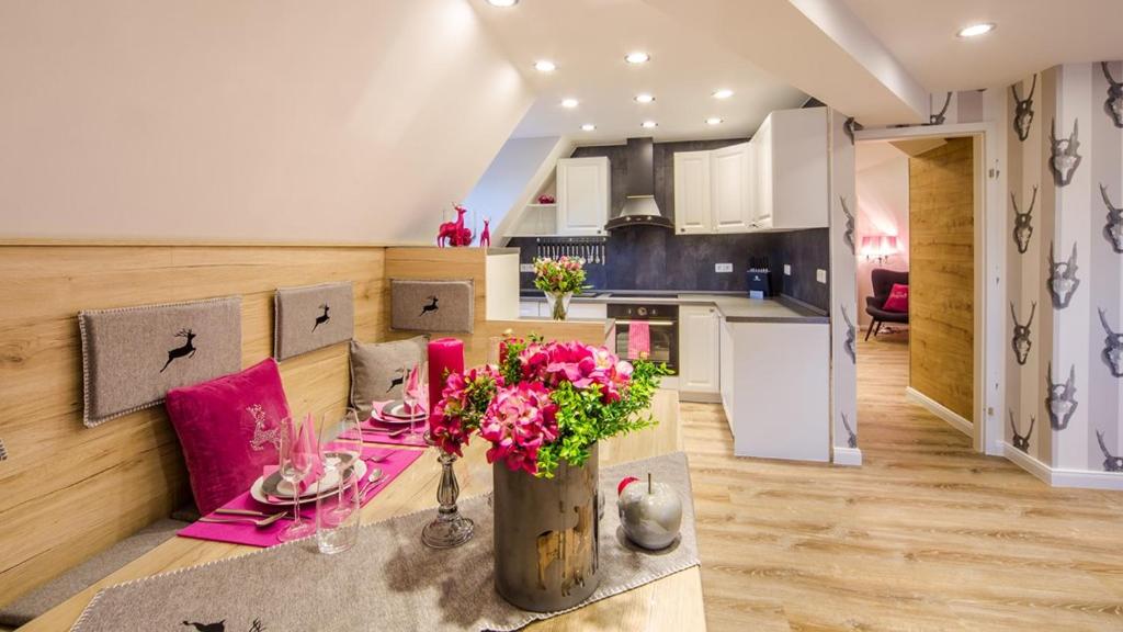 a kitchen and living room with a table with flowers at Luxuslodge Wernigerode in Wernigerode