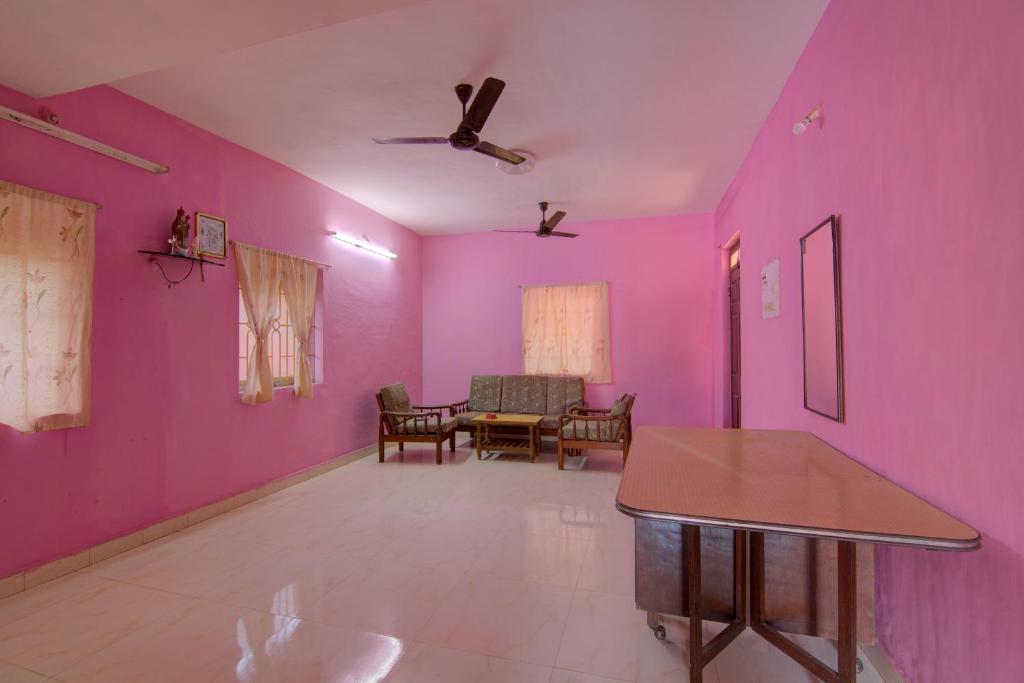 a living room with pink walls and a table at Molly's Nest in Mandrem