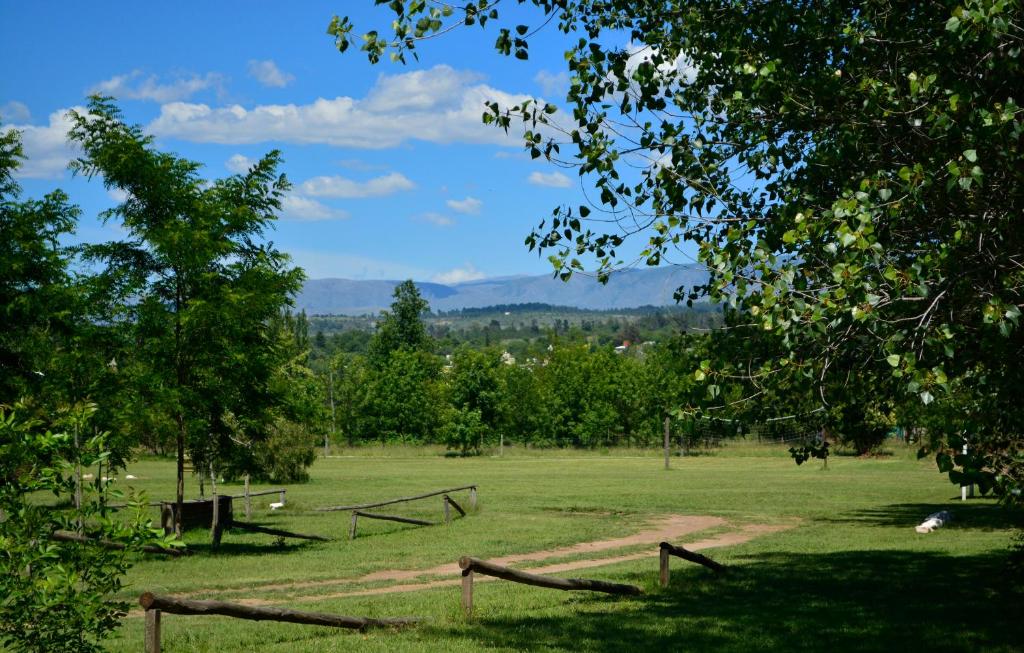 un campo verde con una valla y árboles en La Argentina Complejo en Villa Ciudad de América
