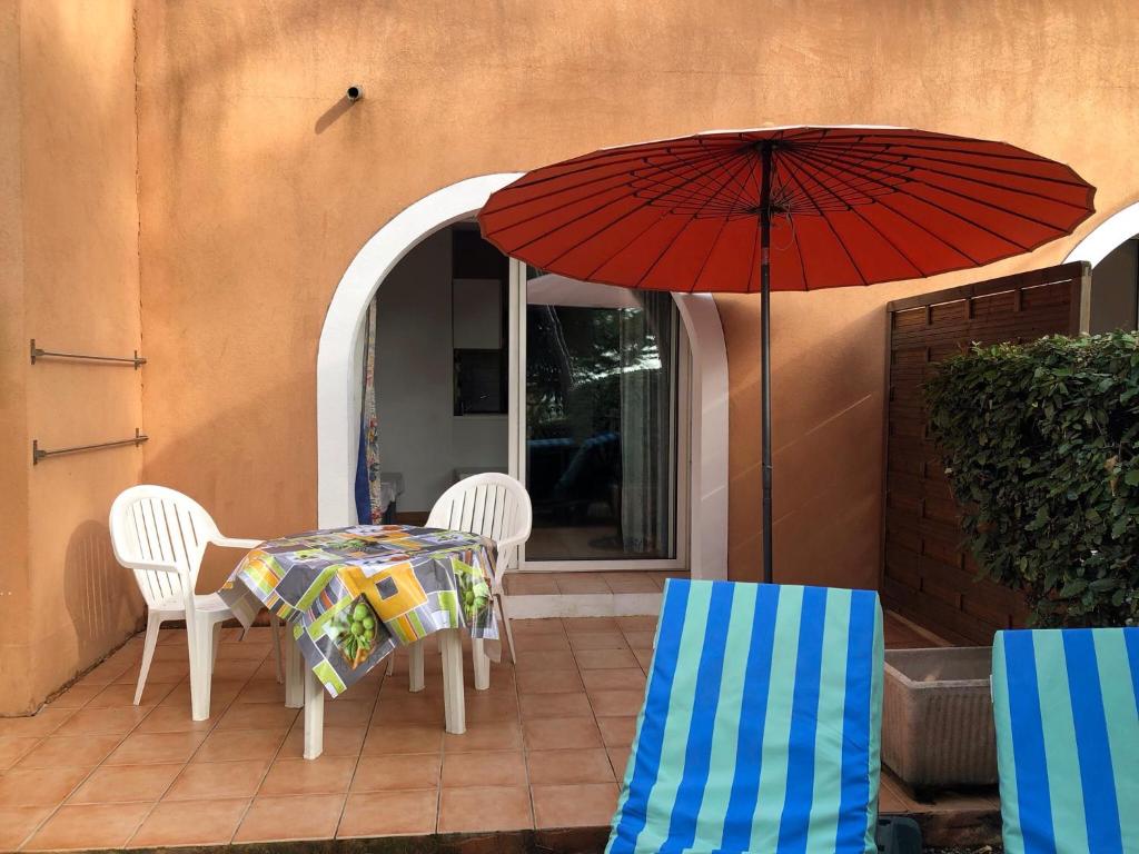 a patio with a table and chairs and an umbrella at 50m Plage T2 Grande Terrasse Vue Mer Climatisé Piscine Chauffée, Parking clos gratuit in Sanary-sur-Mer