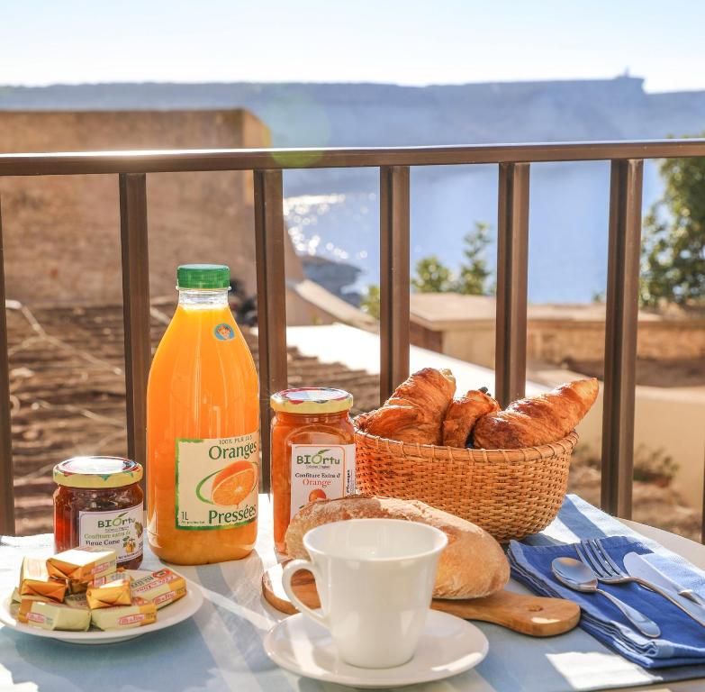 a table with a basket of bread and a bottle of orange juice at Faro di Capo Testa in Bonifacio