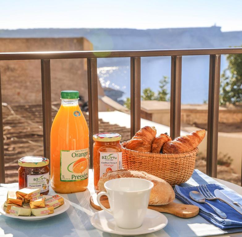 - une table avec un panier de pain et une bouteille de jus d'orange dans l'établissement Faro di Capo Testa, à Bonifacio