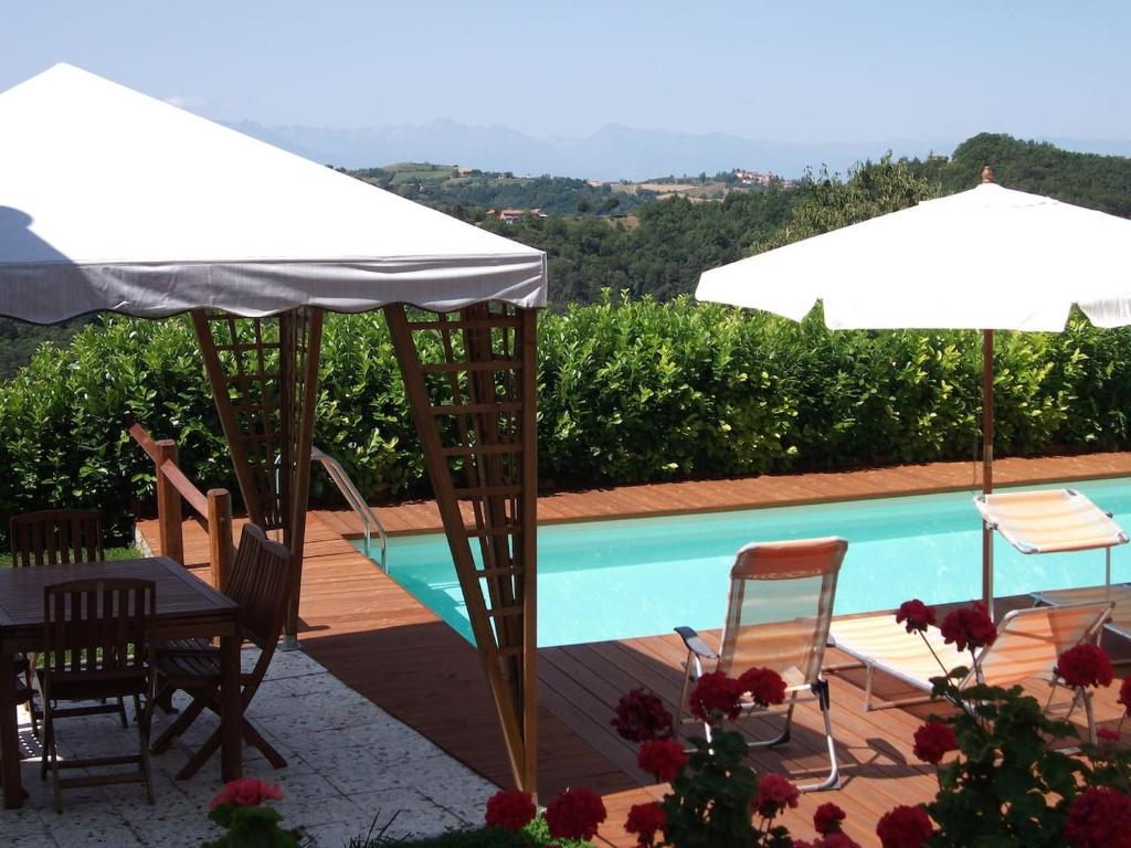 patio ze stołem i parasolami oraz basenem w obiekcie Bricco di Sant' Eufemia w mieście Bossolasco