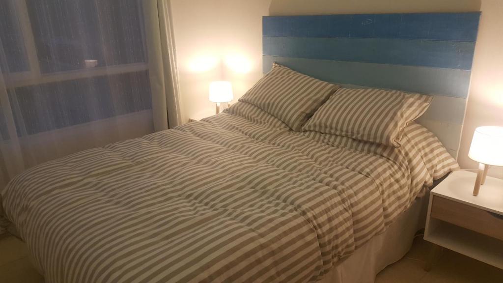 コキンボにあるDpto Marina Oceanoのベッドルーム1室(ストライプのベッドカバー、ランプ2つ付)
