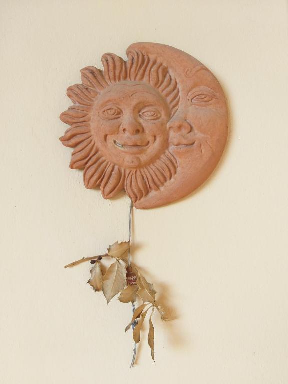 una decoración solar de madera en una pared con hojas en Casa SoleLuna, en Siena