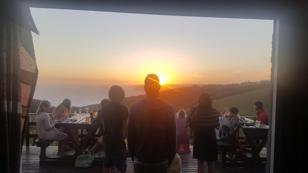 a group of people watching the sunset at a restaurant at The Wild Farm Backpackers in Wilderness