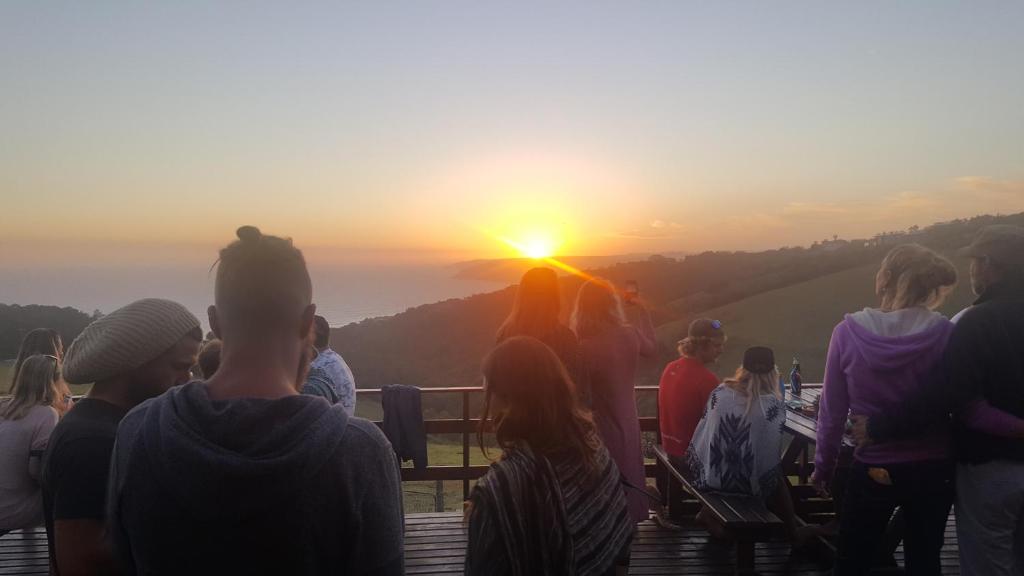 a group of people watching the sunset at the top of a mountain at The Wild Farm Backpackers in Wilderness