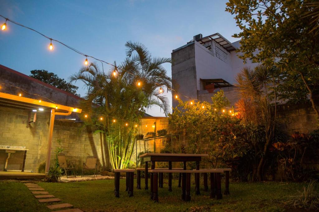 una mesa de picnic en un patio trasero por la noche con luces en Alice y Juancito Boutique Hotel, en Alajuela