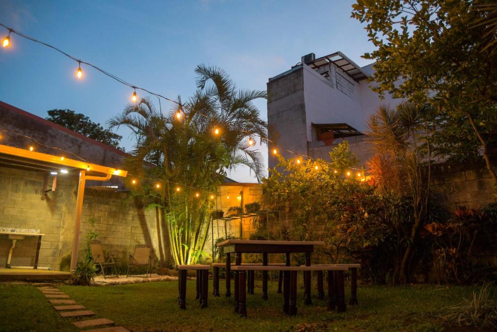 a picnic table in a backyard at night with lights at Alice y Juancito Boutique Hotel in Alajuela City