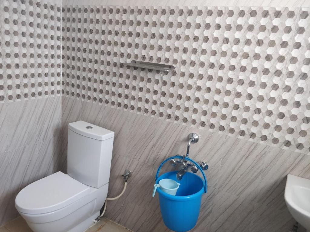 a bathroom with a toilet and a blue bucket at Tulip Suites in Coimbatore