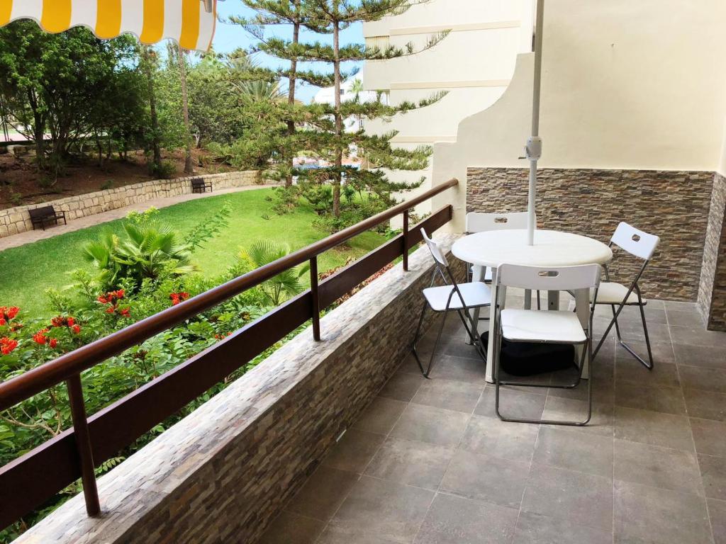 a balcony with a table and chairs and a garden at Lovely 1-bedroom apartment with a big terrace, Las Americas, Tenerife in Arona