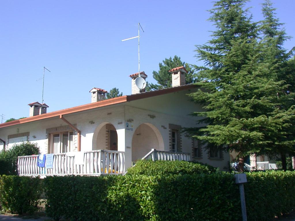 una casa bianca con un portico e un albero di Villa Menazzi a Lignano Sabbiadoro