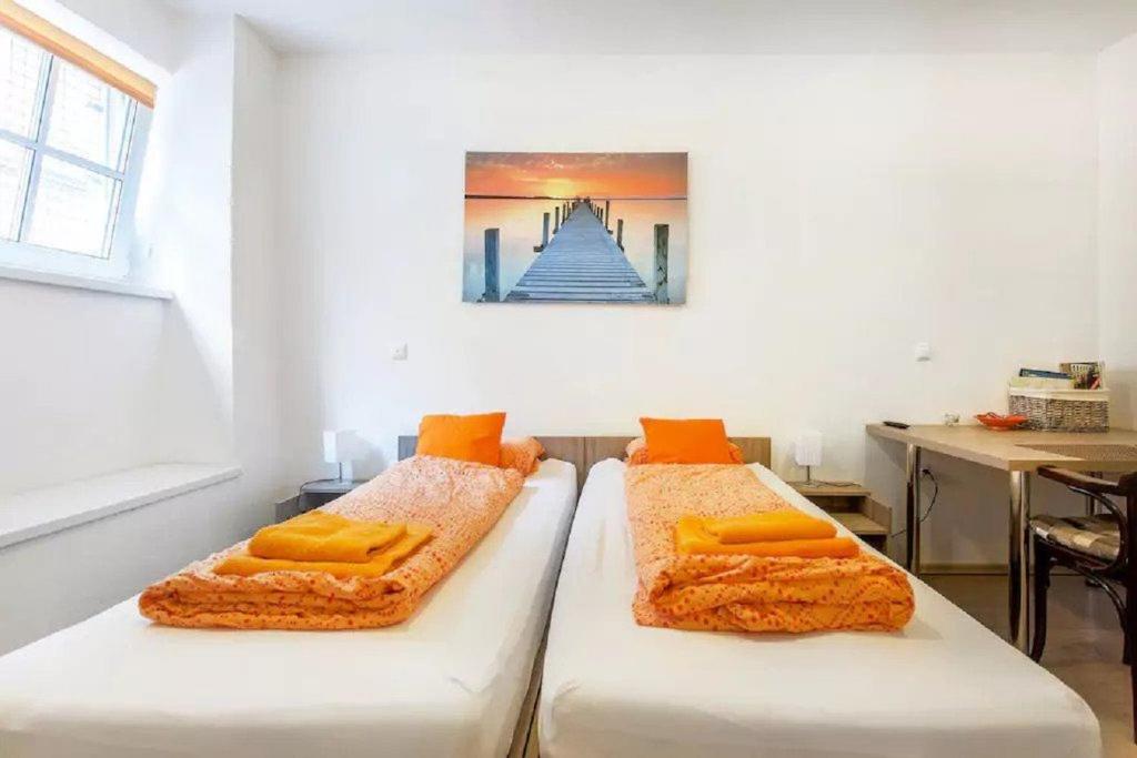 2 camas con almohadas de color naranja en una habitación en Apartments FABRKA, en Liubliana